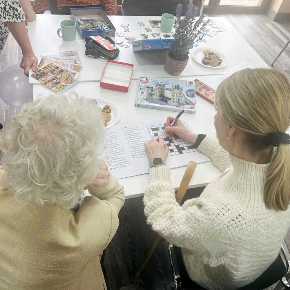 Visitors to the Home Instead Farnborough Lavender Lounge enjoying a crossword