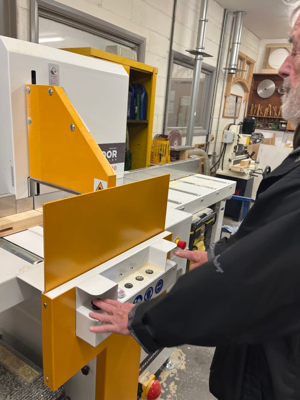 A person uses a woodworking machine in a workshop, pressing buttons on the control panel. - Home Instead