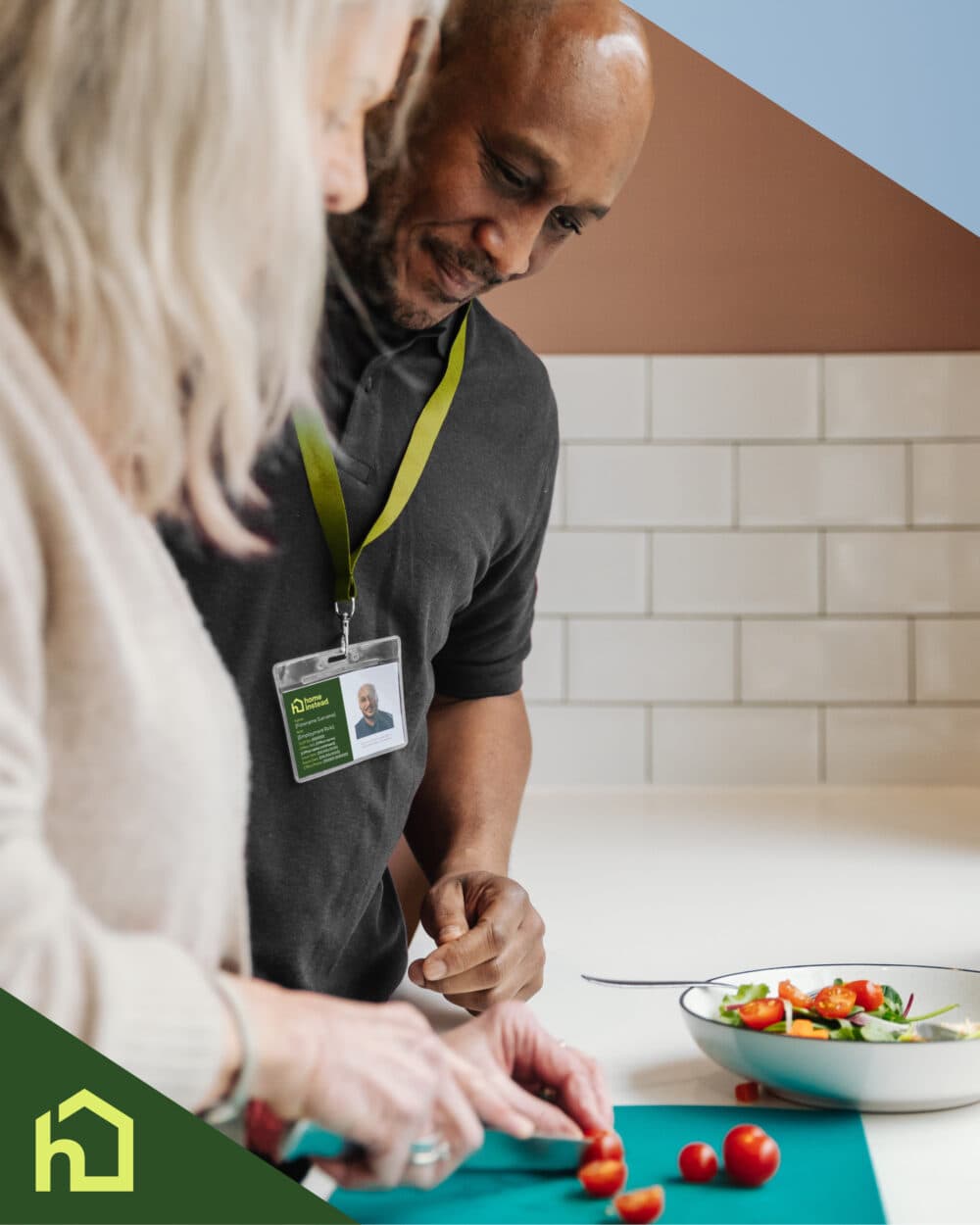Two people slice vegetables together in a kitchen, both wearing ID lanyards. A bowl of salad is nearby. - Home Instead