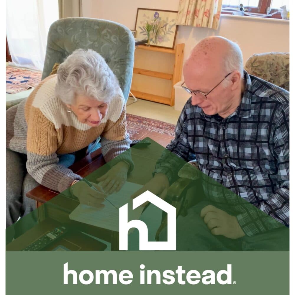 Elderly woman and man reviewing papers together at home, with "home instead" logo at the bottom. - Home Instead