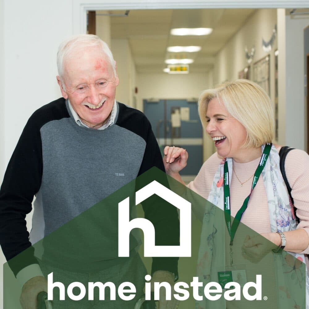 An elderly man and a smiling caregiver walk together; "home instead" logo is overlaid at the bottom. - Home Instead