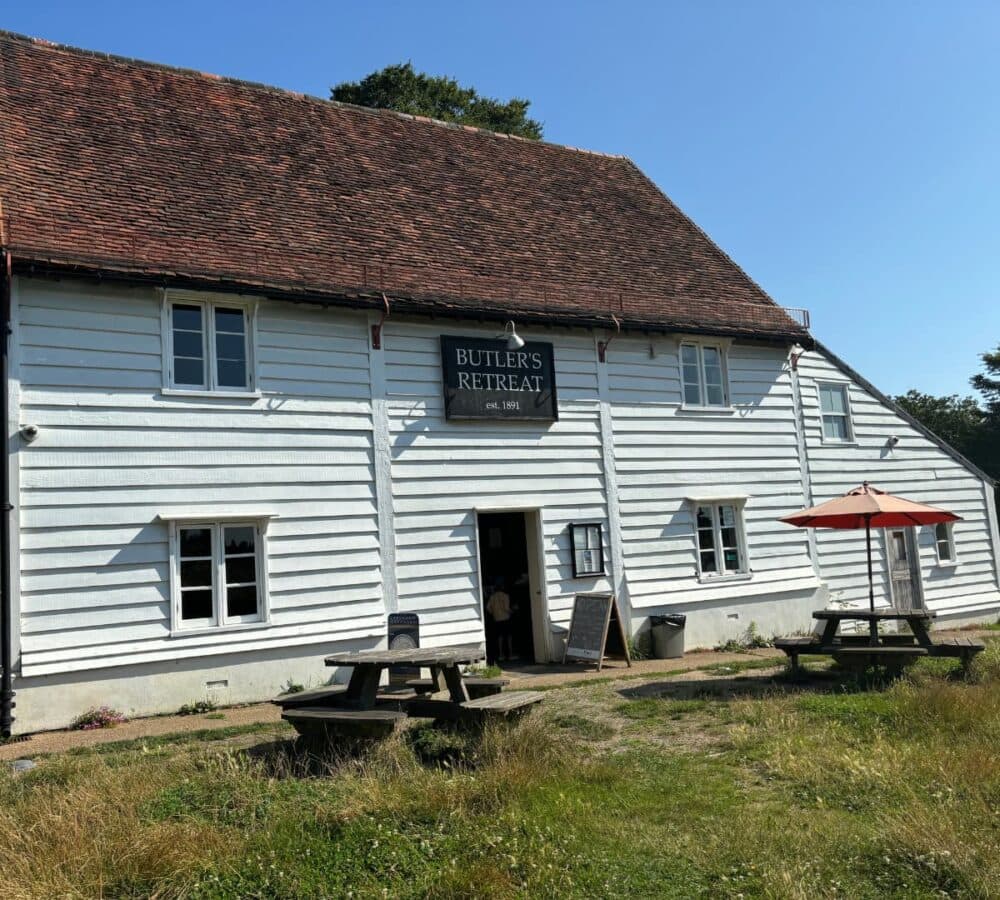 A big retreat house with white paint and many windows and a huge roof surrounded by green grass