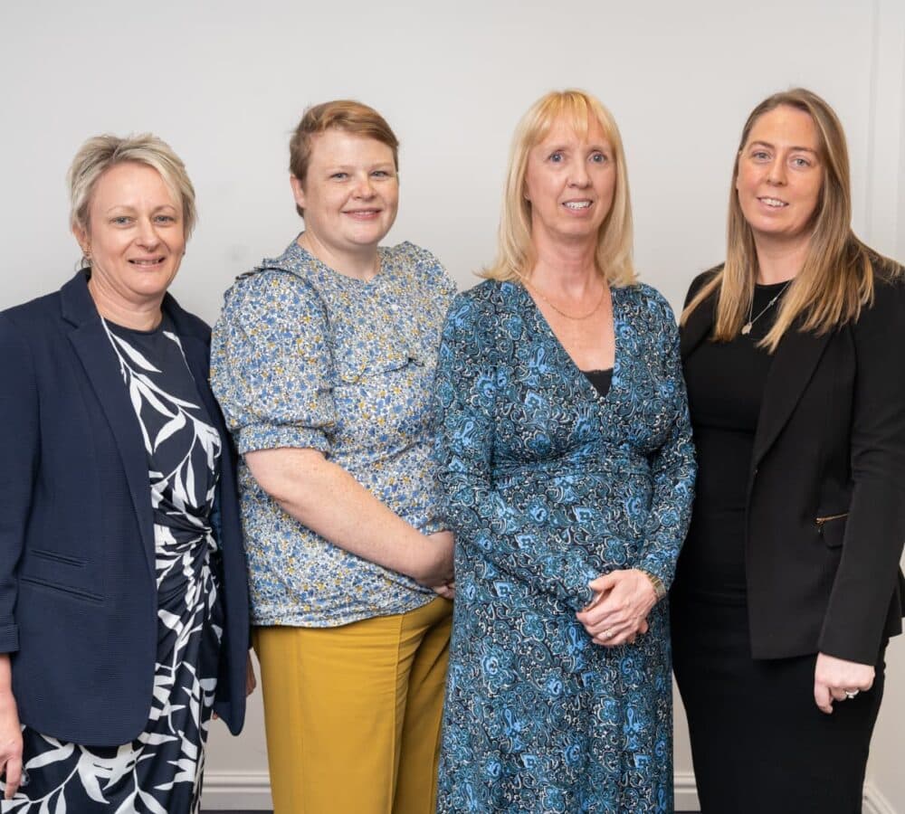 Four women standing and all are happy and smiling