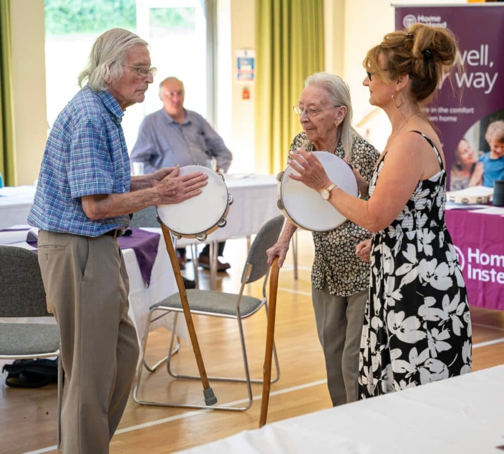 Two older adult dancing while holding a tambourine inside the hall