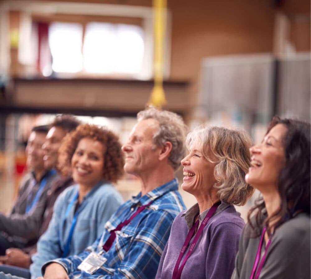 A group of people listening and sitting inside a room