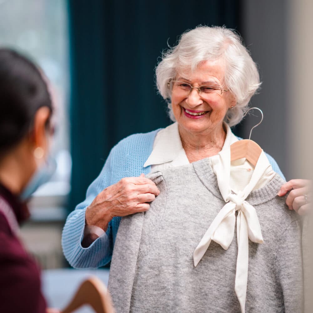 Home Instead carer helps her female client to choose clothes