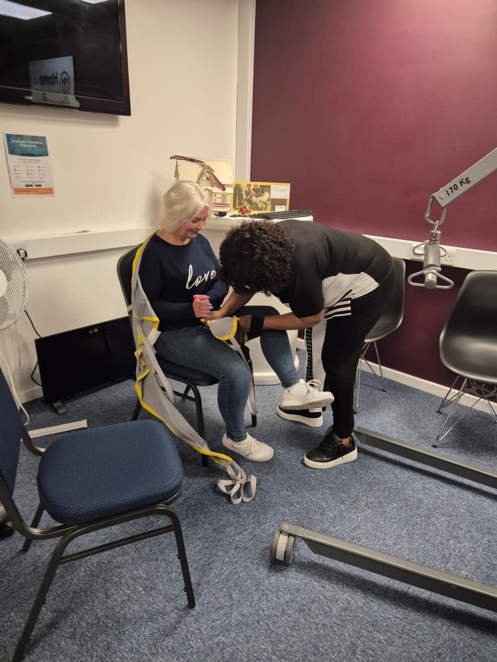 Daisy suspended in a Birdie hoist while Deborah adjusts the spreader bar.