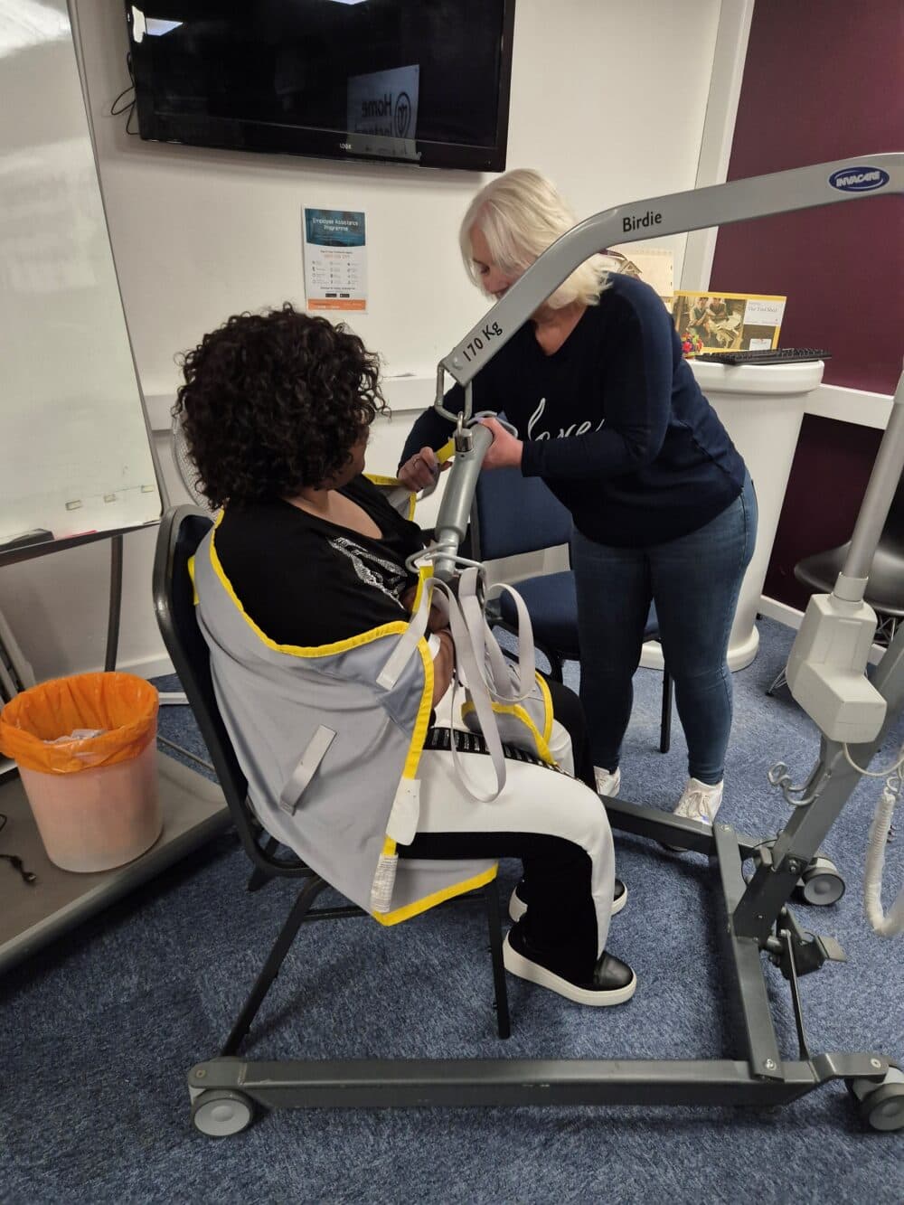 Deborah unfolds the sling as Daisy waits, smiling, before practice begins.