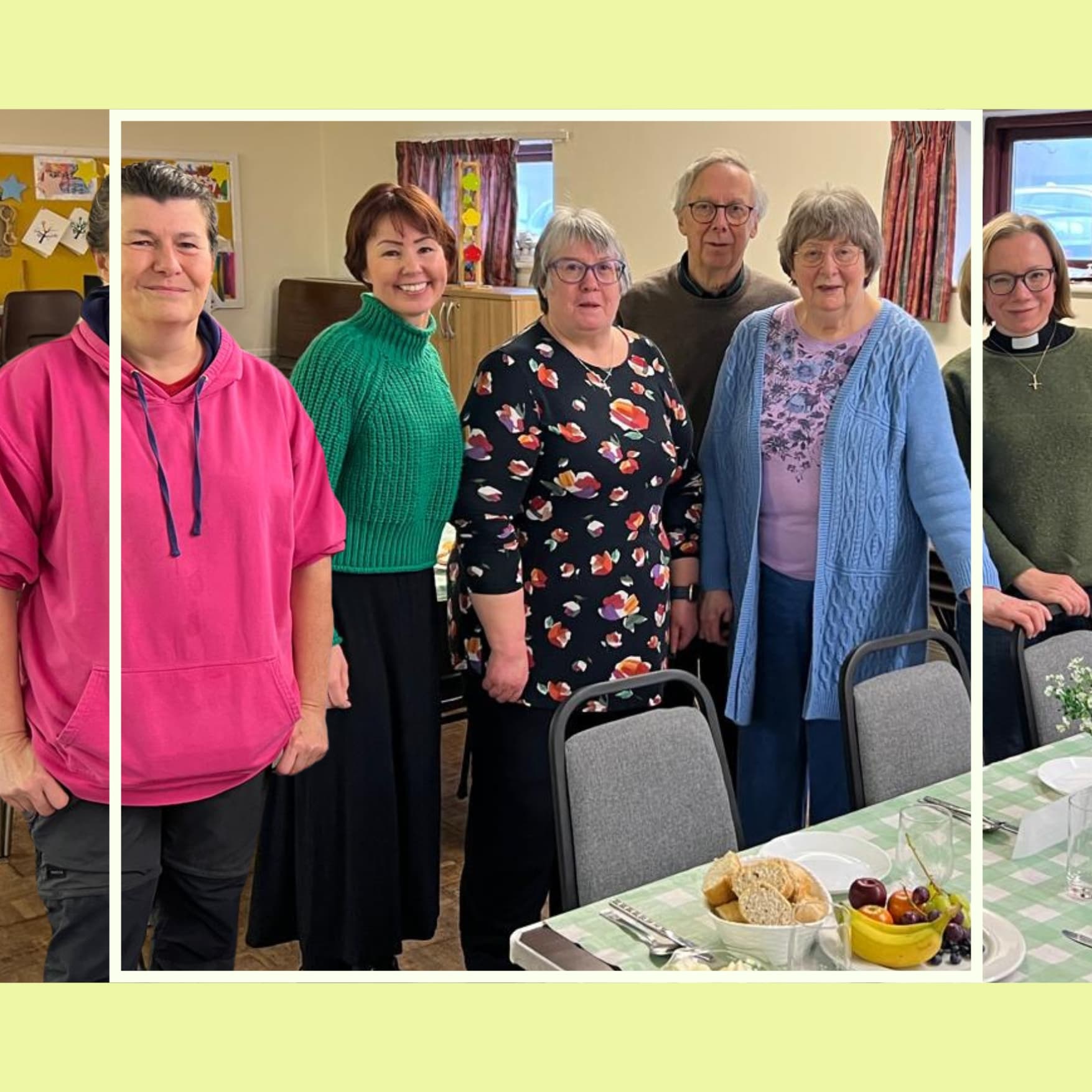Six adults stand smiling behind a table set with plates of food in a cozy, well-lit room. - Home Instead