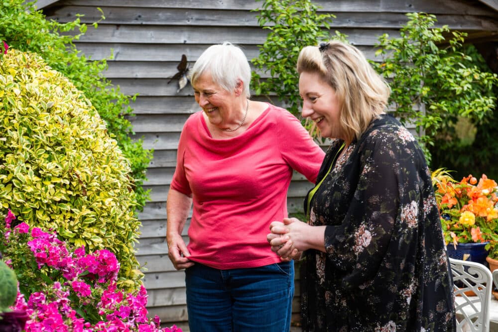 Client with Carer in garden looking at flowers
