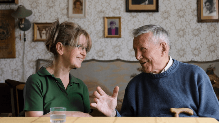 A man and a woman sitting at the kitchen table talking