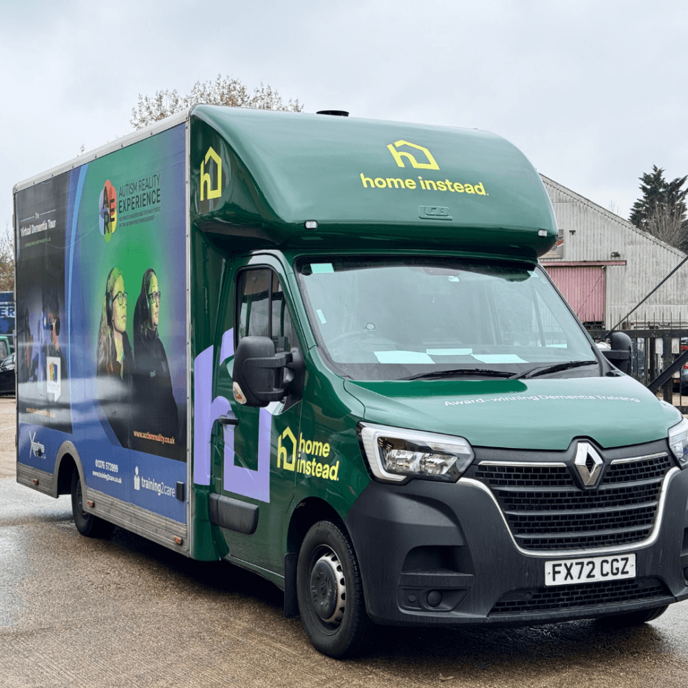Alt Text: Green Home Instead Renault van with Autism and Dementia training visuals and branding