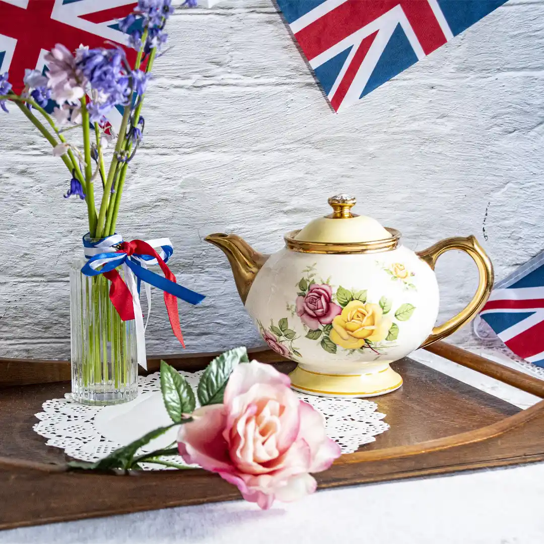 Teapot and flowers arranged on a table among Union Jacks for VE day celebrations