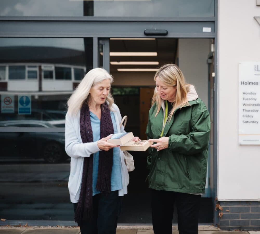 Two woman looking at a book happy and smiling while going out of the library