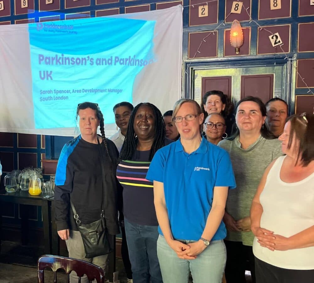 Group of people men and women standing with a projector at the side inside a room