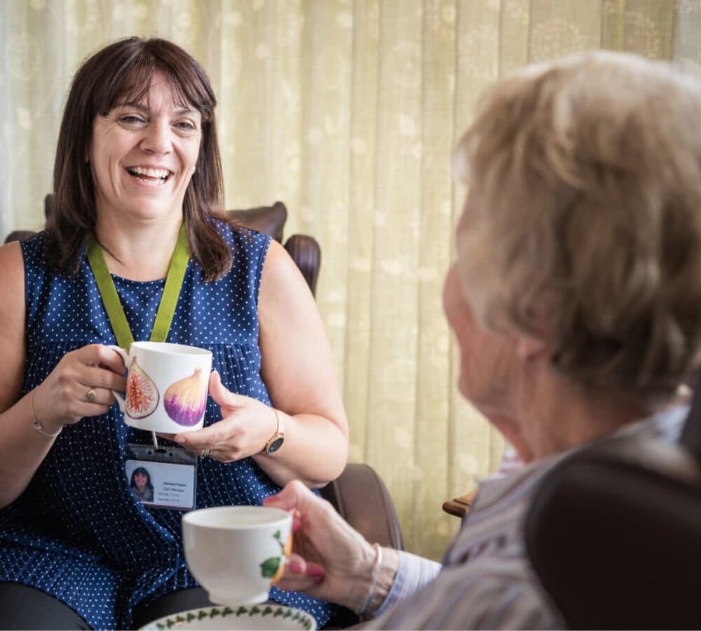 Two women having a cup of coffee together both happpy and smiling