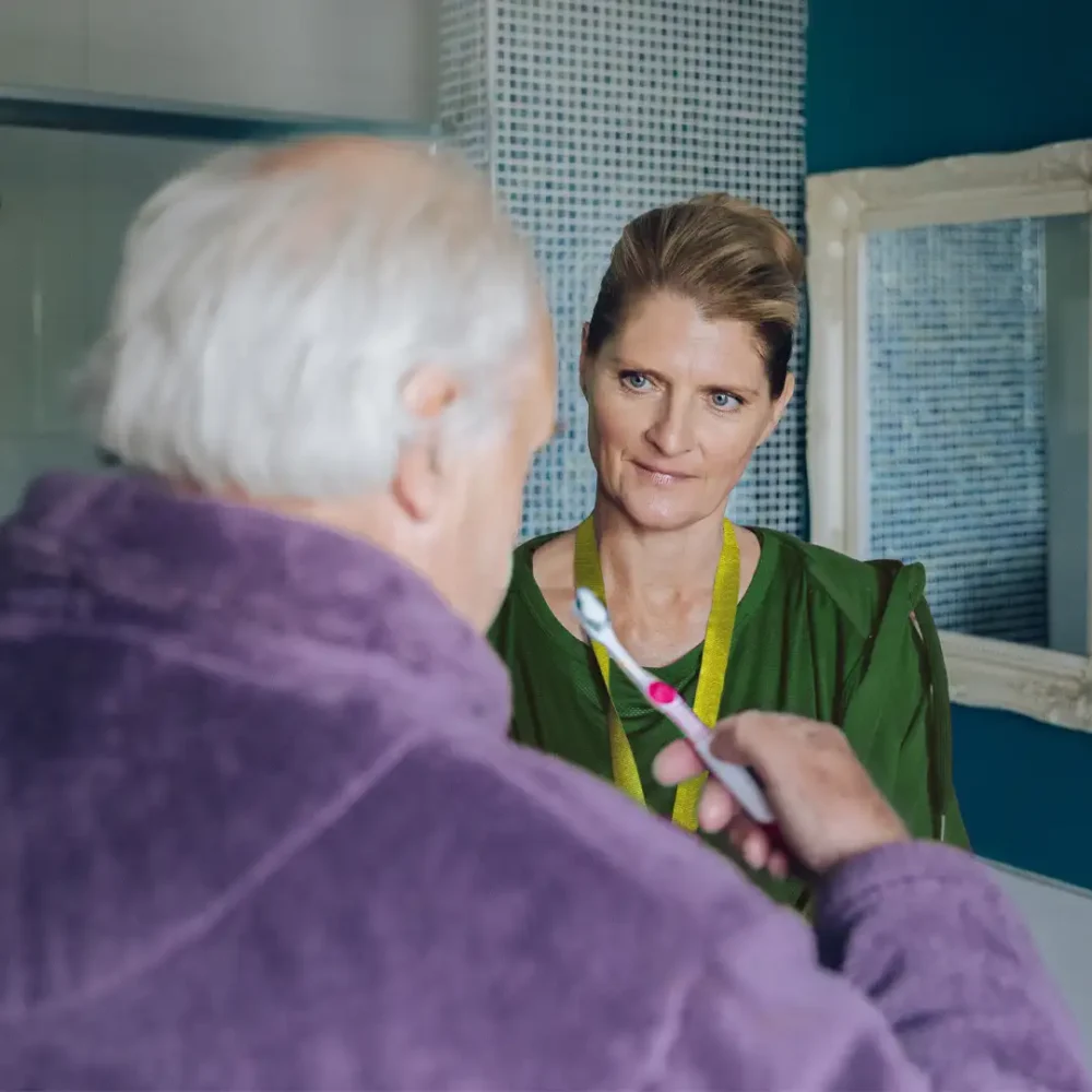 Home Instead Care Professional supporting her client to brush his teeth
