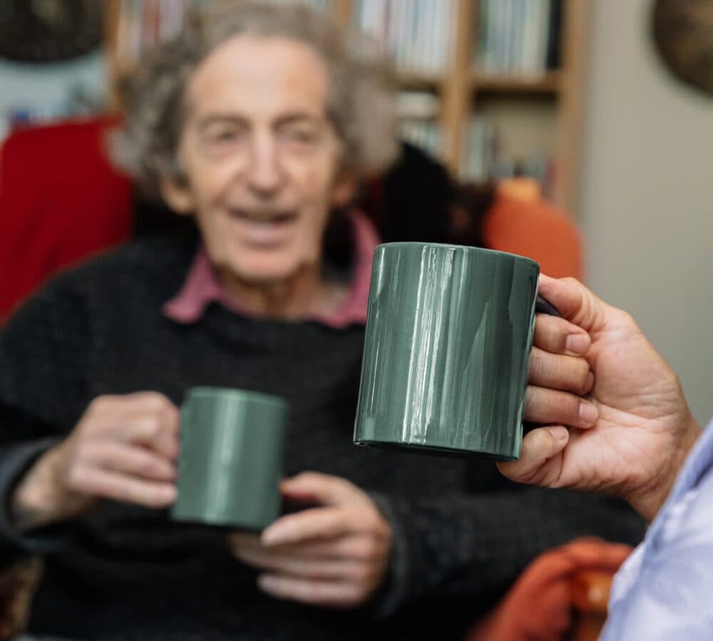 Two people holding a green mug with coffee