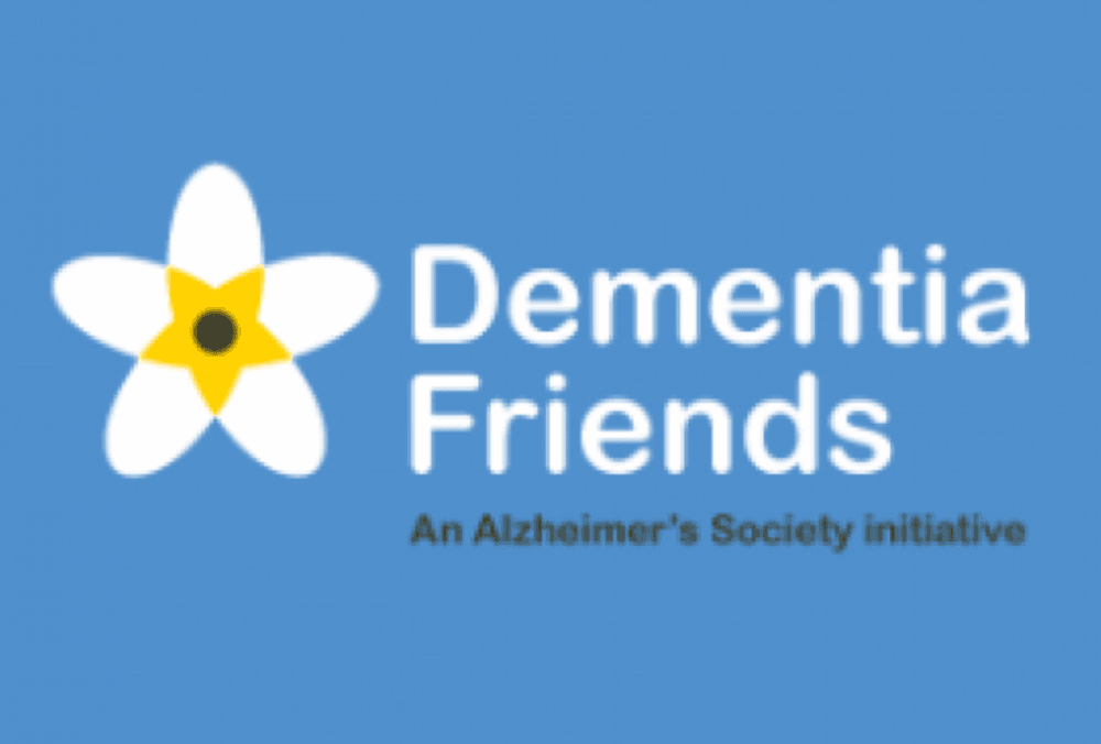 Dementia Friends logo with a white and yellow flower and blue background; Alzheimer’s Society initiative. - Home Instead