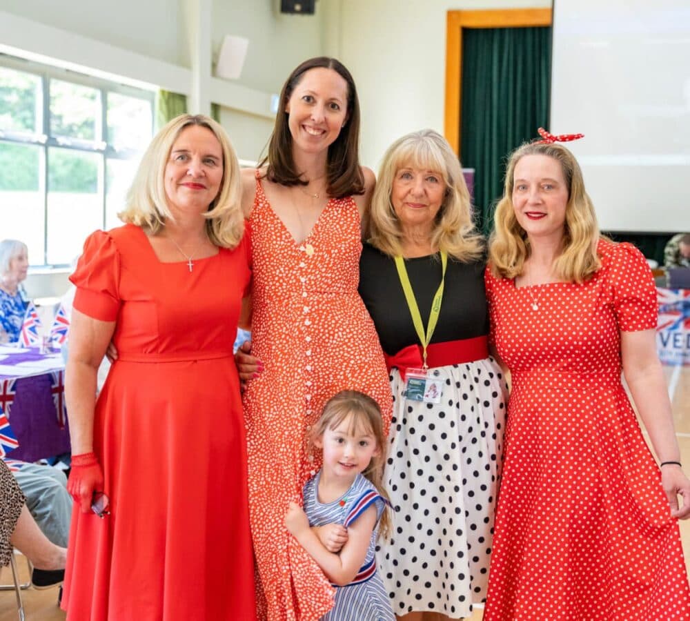 Four women wearing colourful clothes and with a girl all are happy and smiling inside the hall
