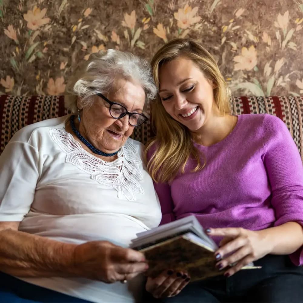 Care professional reminiscing with client looking through photo albums