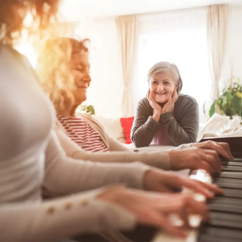 Elderly lady sitting enjoying music being played at a piano
