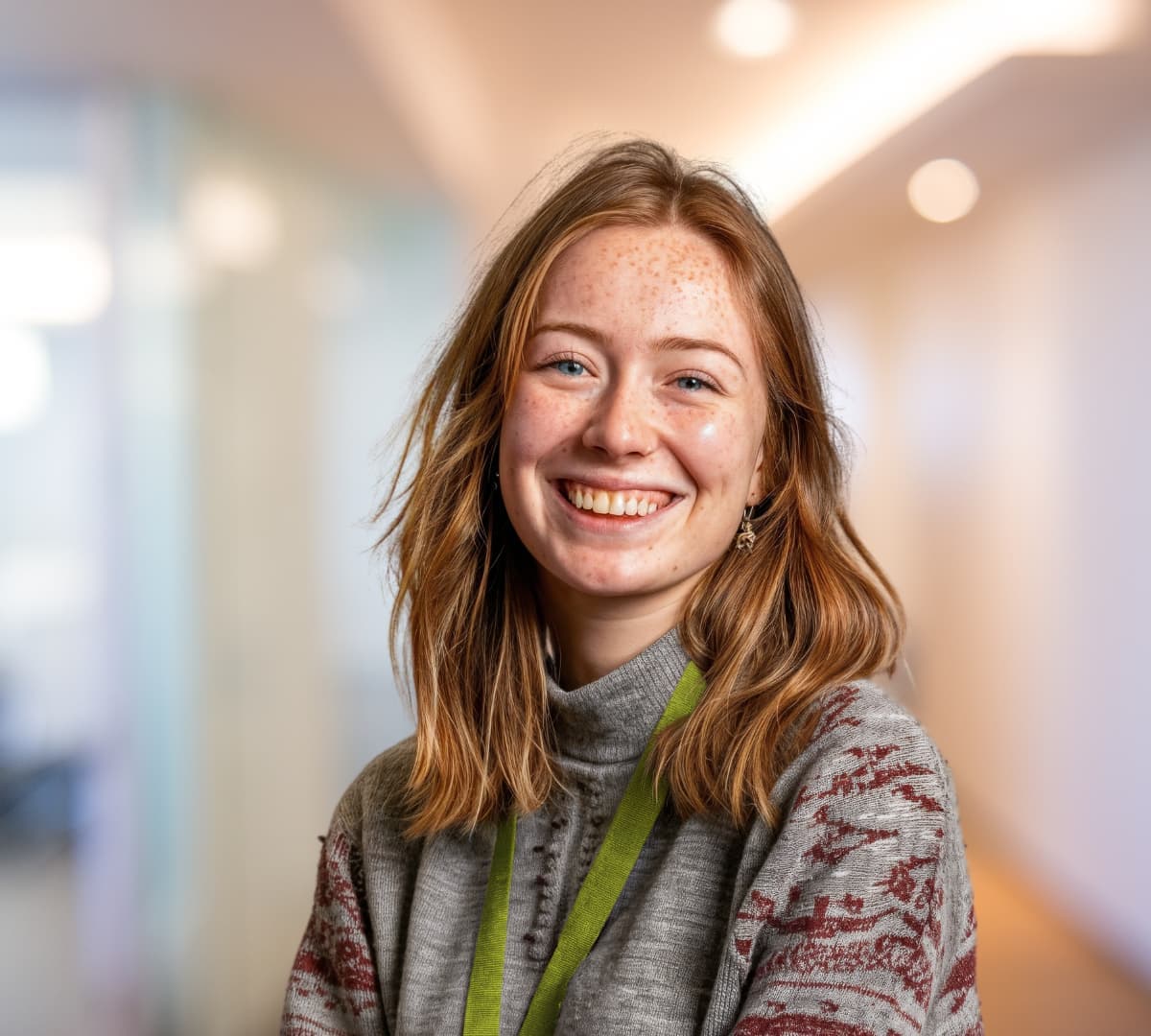 A woman with long brown hair smiling and happy while inside the office