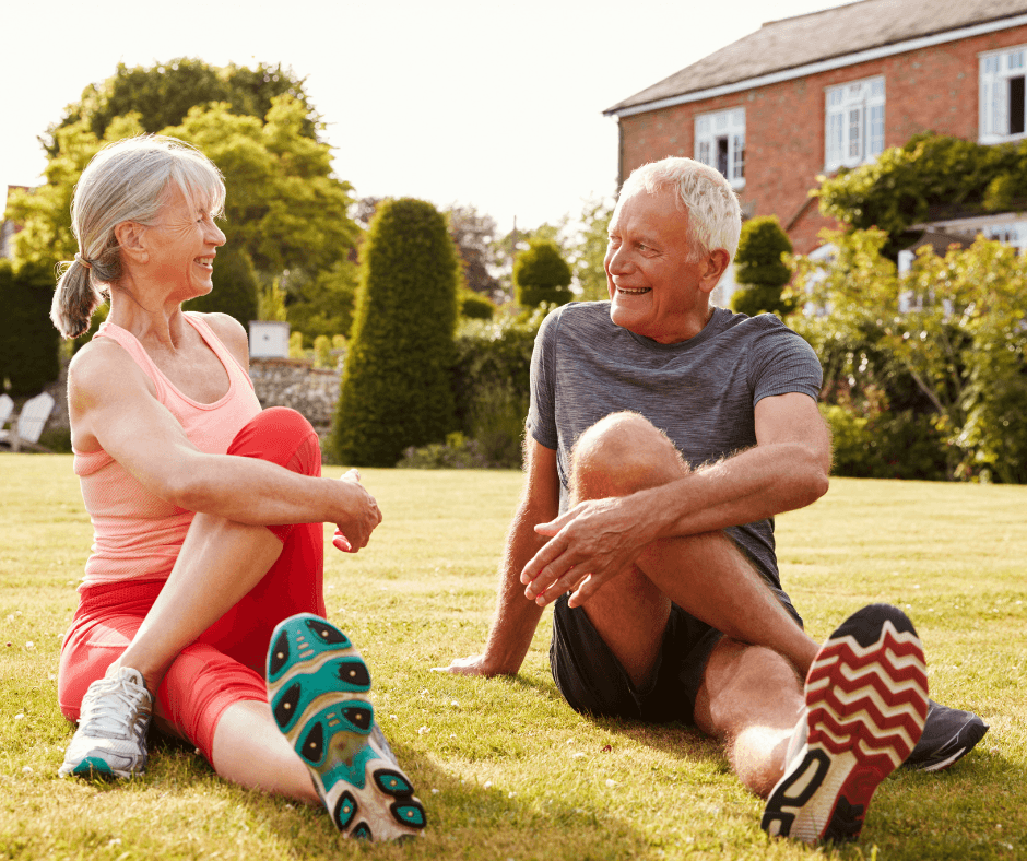 Older couple stretching and smiling together in a sunny garden