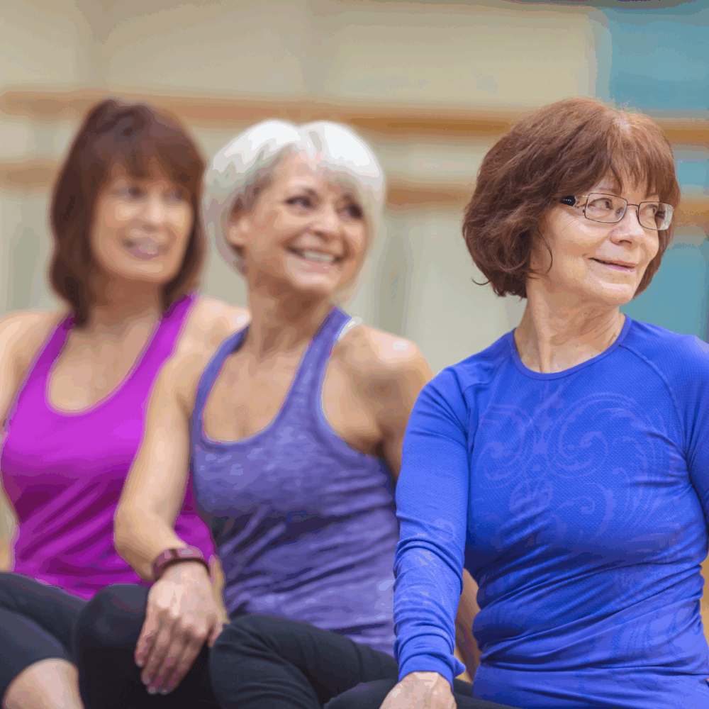Group of older women smiling during an indoor seated exercise class