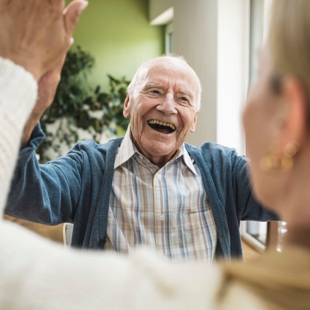 Elderly man looking very happy and rejoicing, and giving a young woman who has her back to the camera a high-five