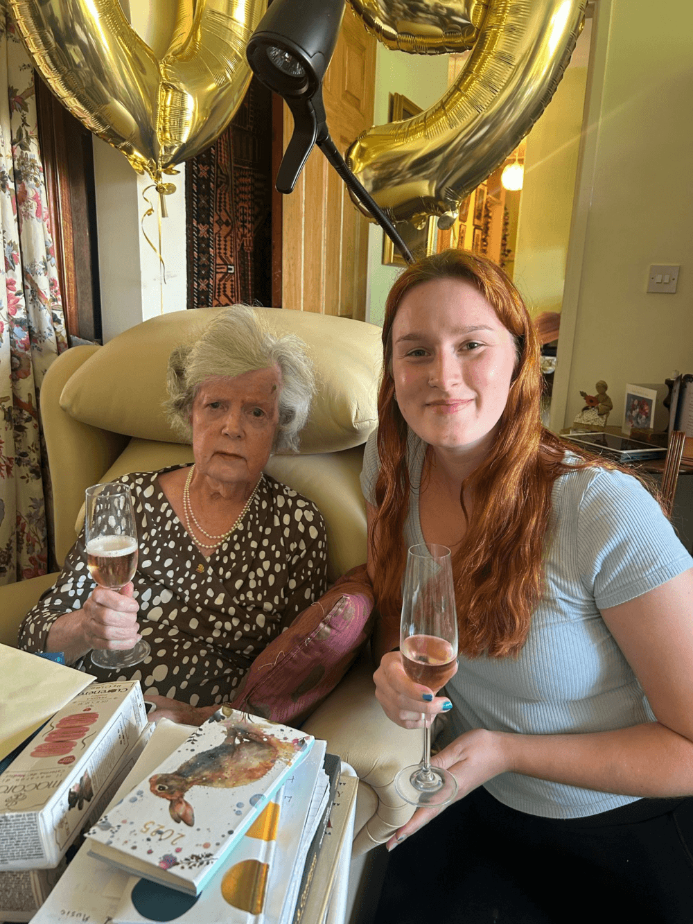 female client and care pro celebrating 90th birthday, drinks in their hands