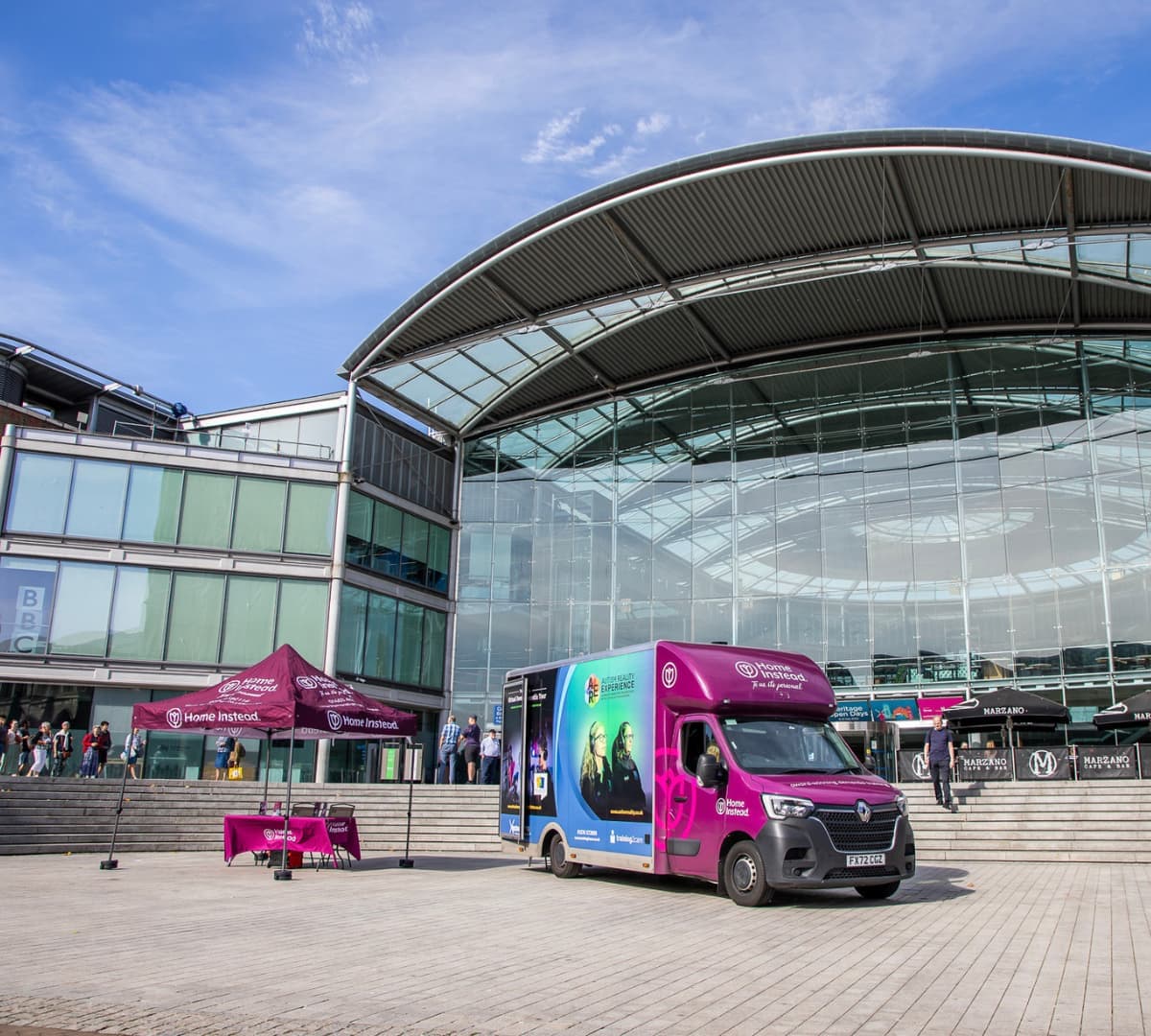 A purple big dementia bus parked outside with a tent beside it