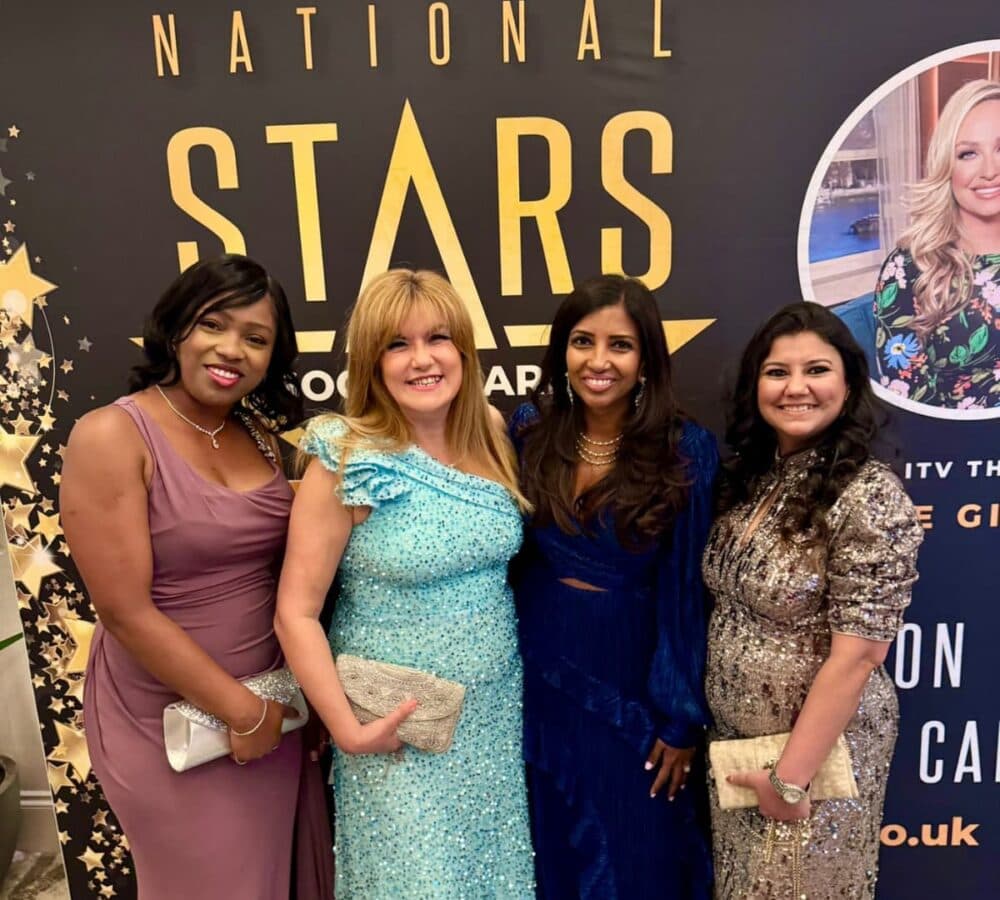Four women wearing long gowns all happy and smiling