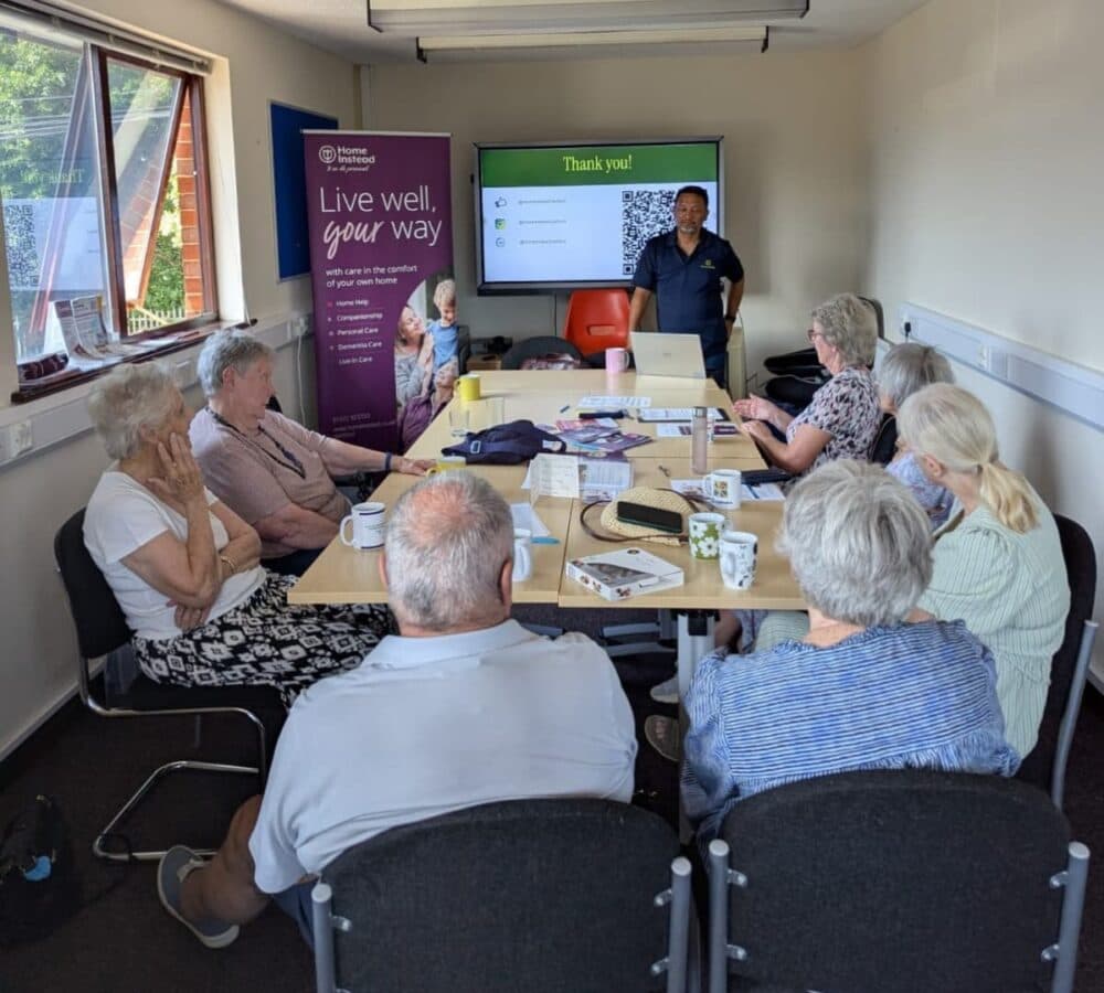 Group of older adult sitting on a chair with long table while listening to their lecturer