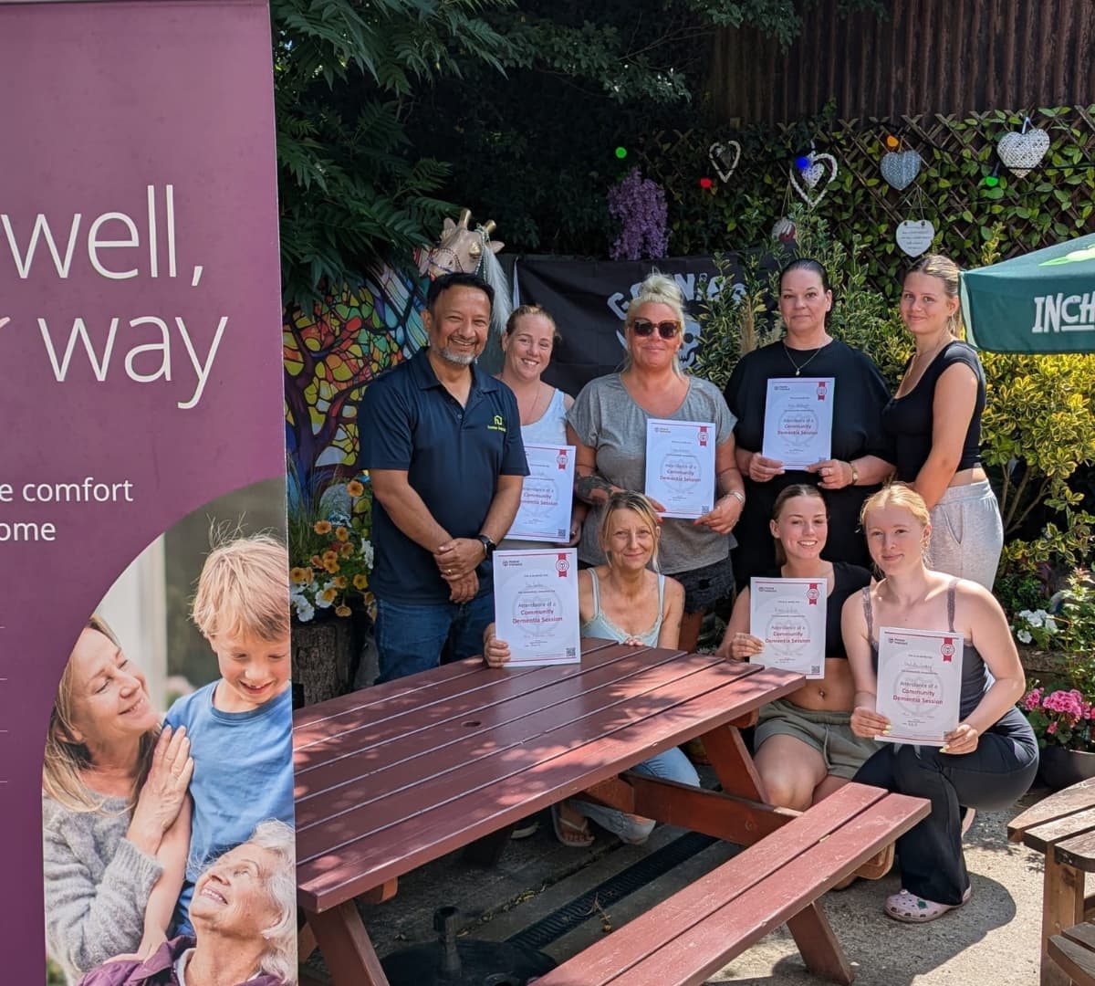 Seven ladies holding a certificate with their male trainer outdoors all happy and smiling