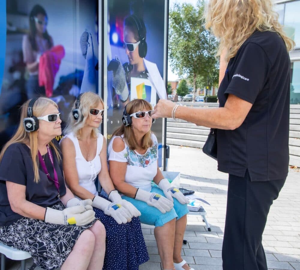 Three people listening together while sitting down and wearing headsets and sunglasses while listening to the instructor