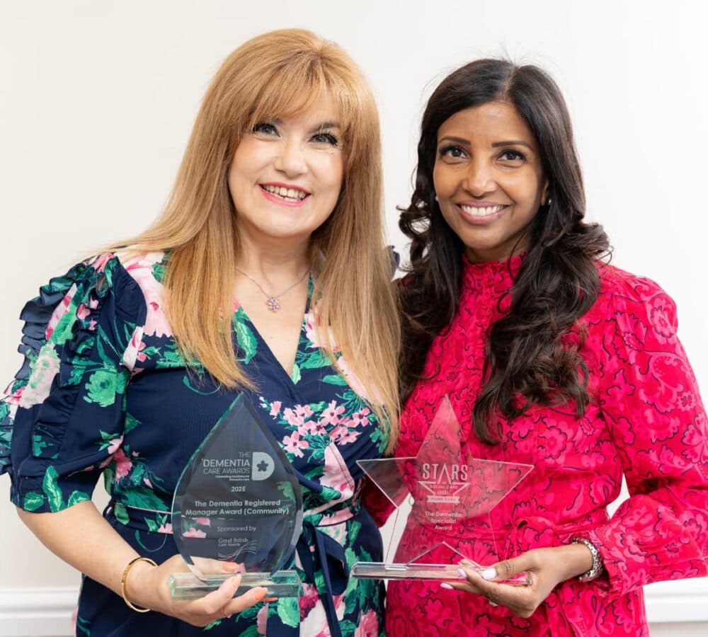 Two women both smiling while holding an award together