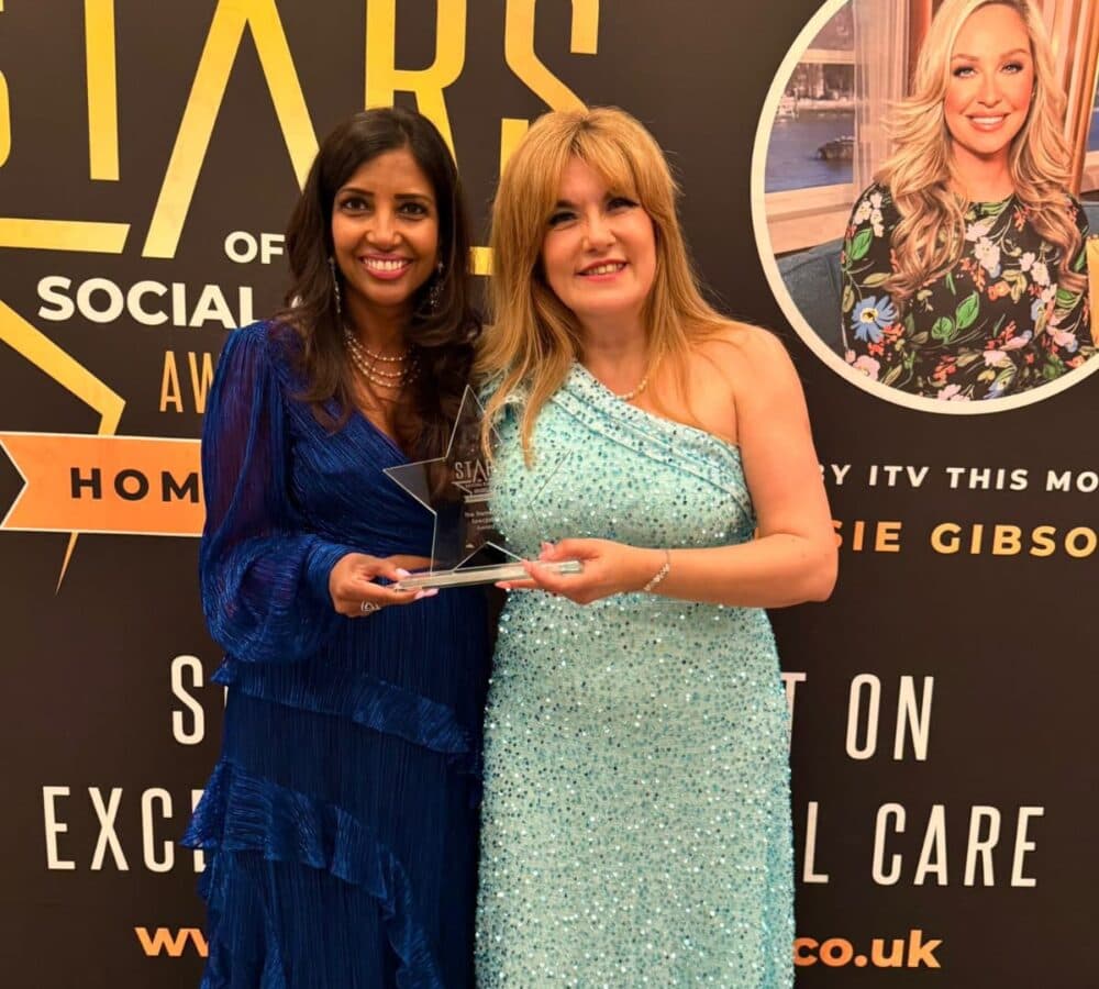 Two woman wearing long gown and holding an award