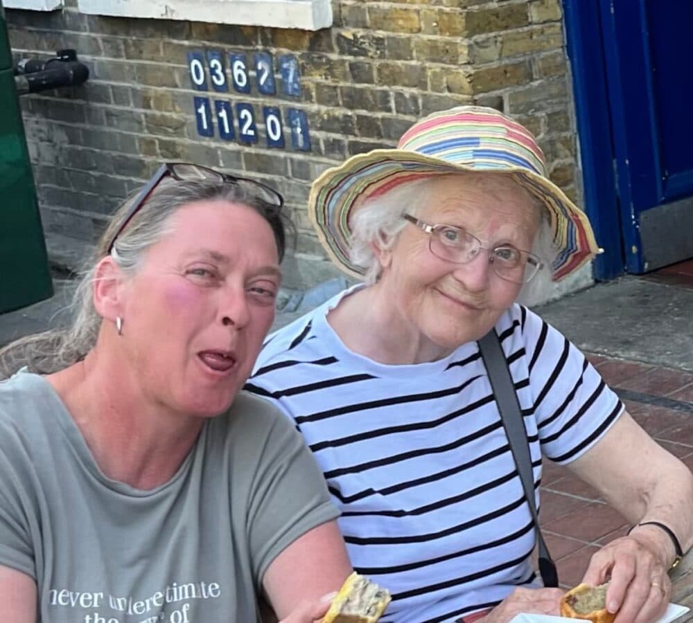 Two women smiling while eating outdoors