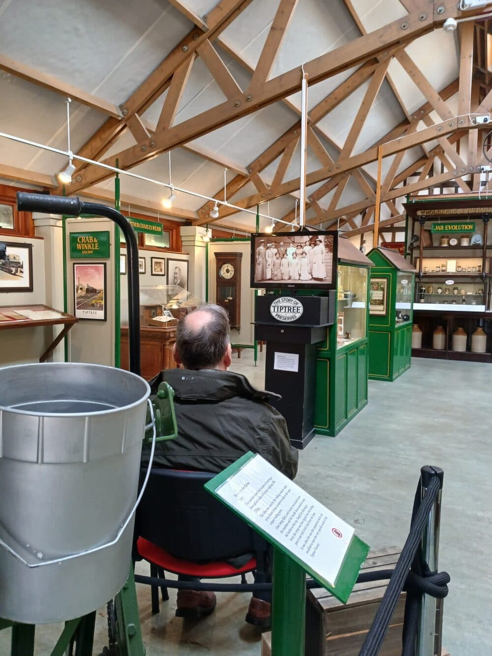 Elderly client enjoying a companionship outing at the Tiptree Jam Factory, exploring the displays and local produce.