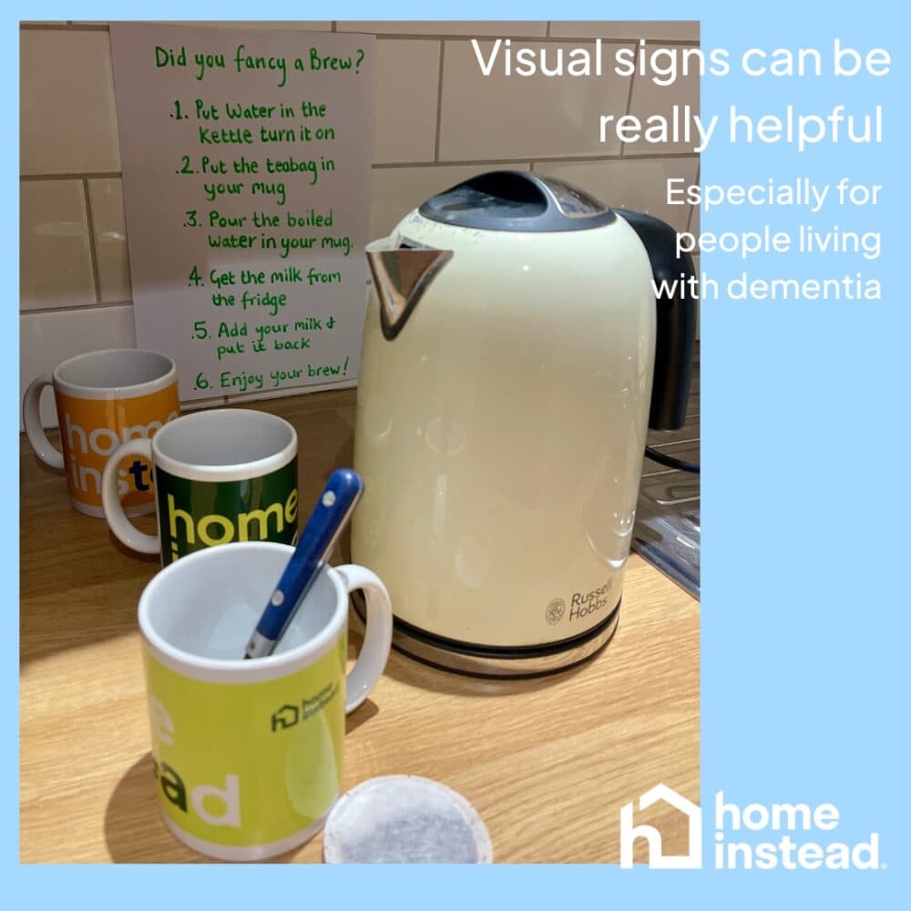 A kettle and mugs with a step-by-step tea-making sign, helpful for people living with dementia. - Home Instead
