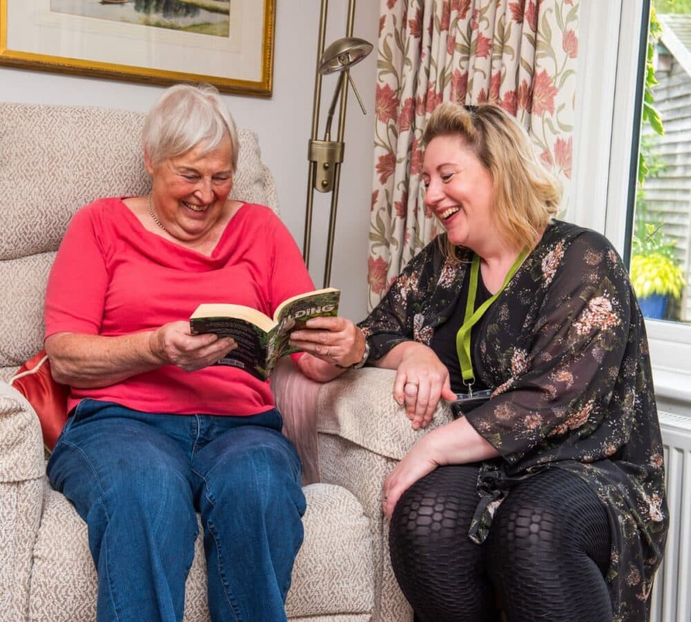 Two women reading a book together inside the house