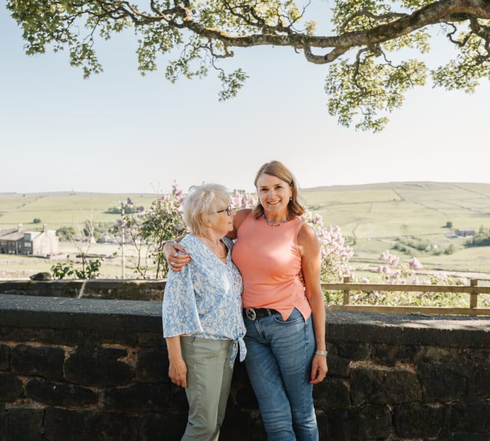 Two women standing in front of a field both happy and smiling
