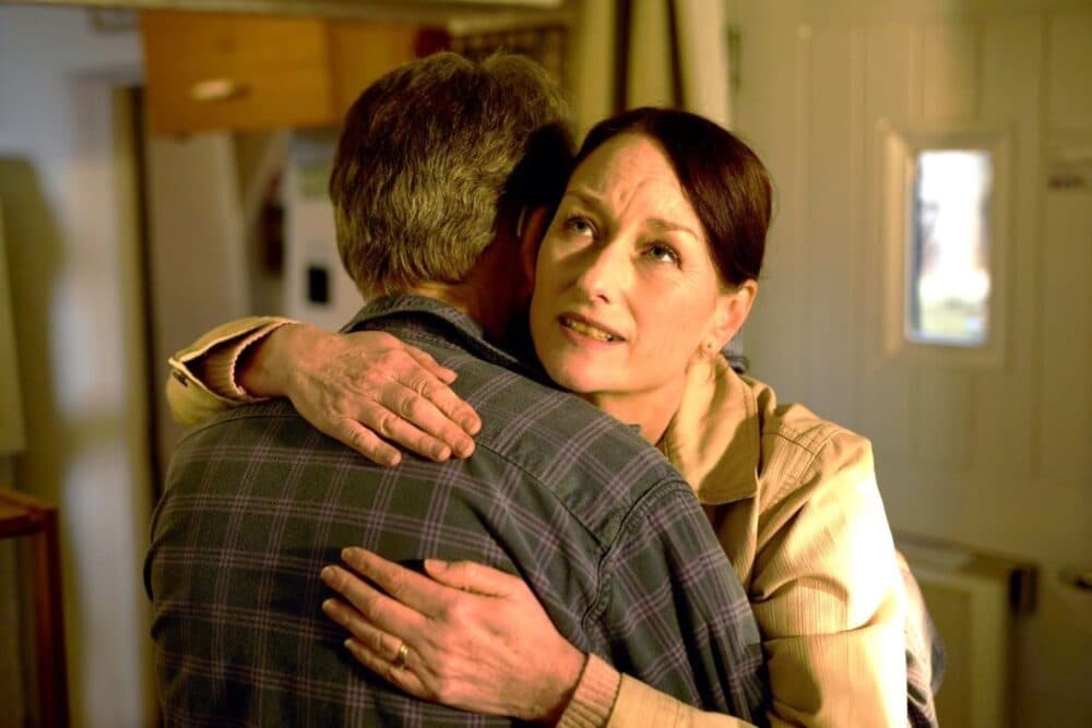 Elderly man hugging younger woman, who has a concerned look on her face