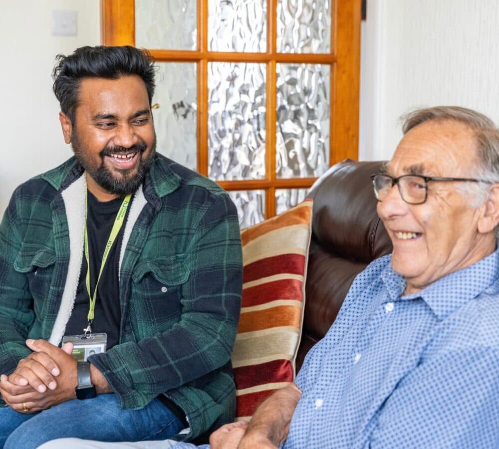Two men chatting together both happy and smiling inside the house