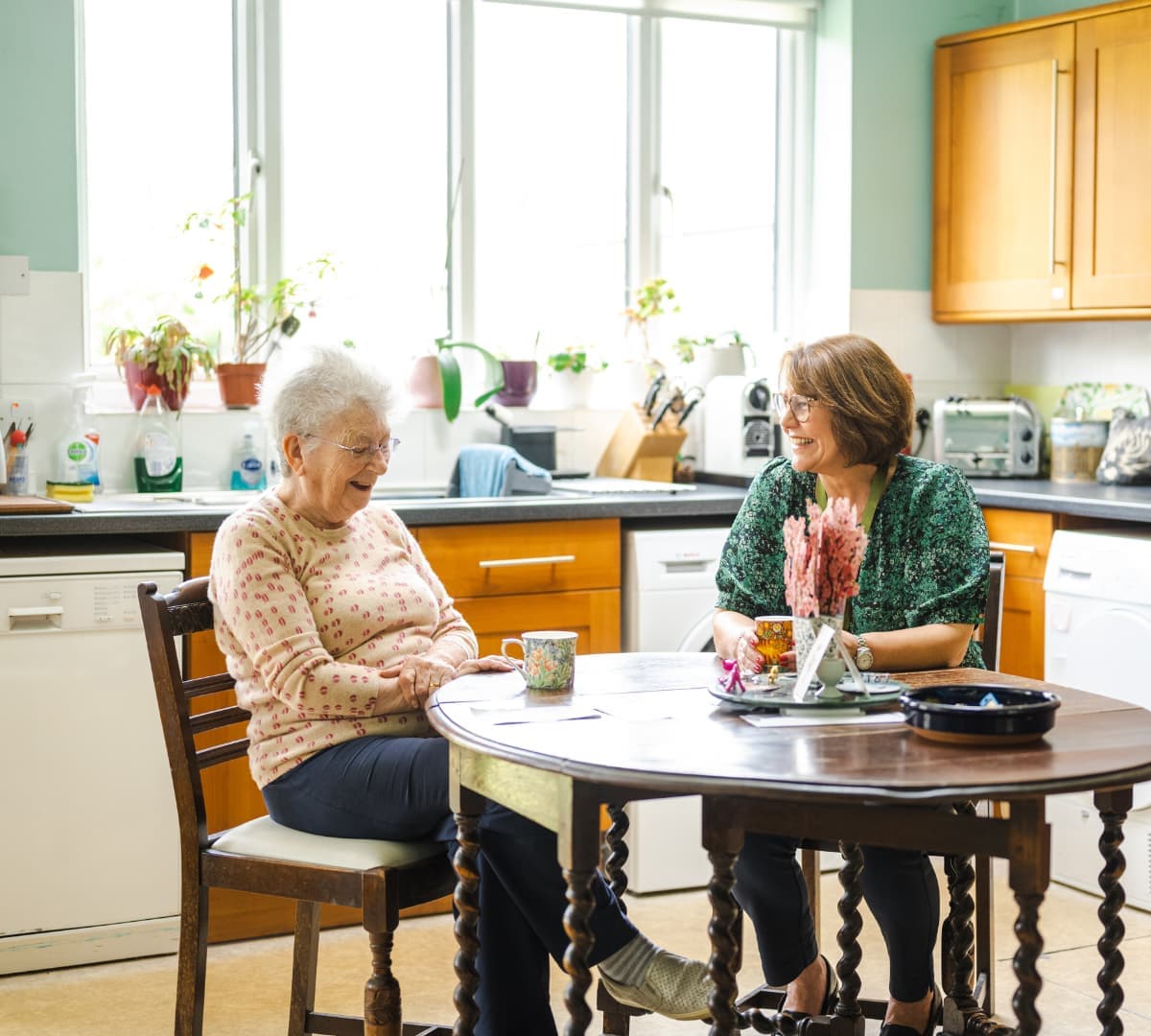 Two women having coffee together happy and laughing while having coffee together