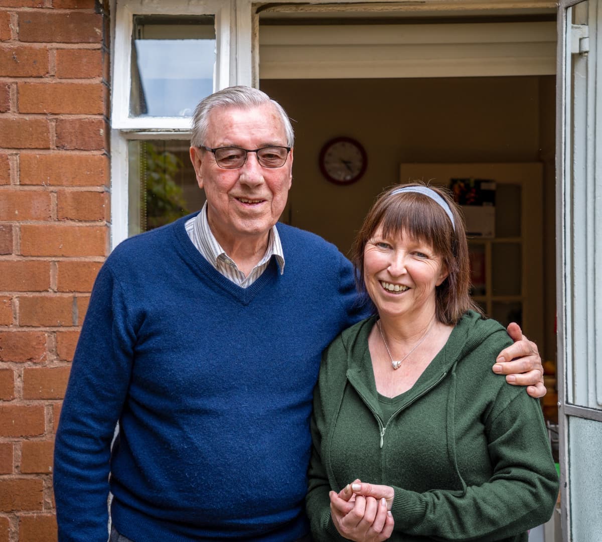 Two people happy and smiling while standing in front of the house