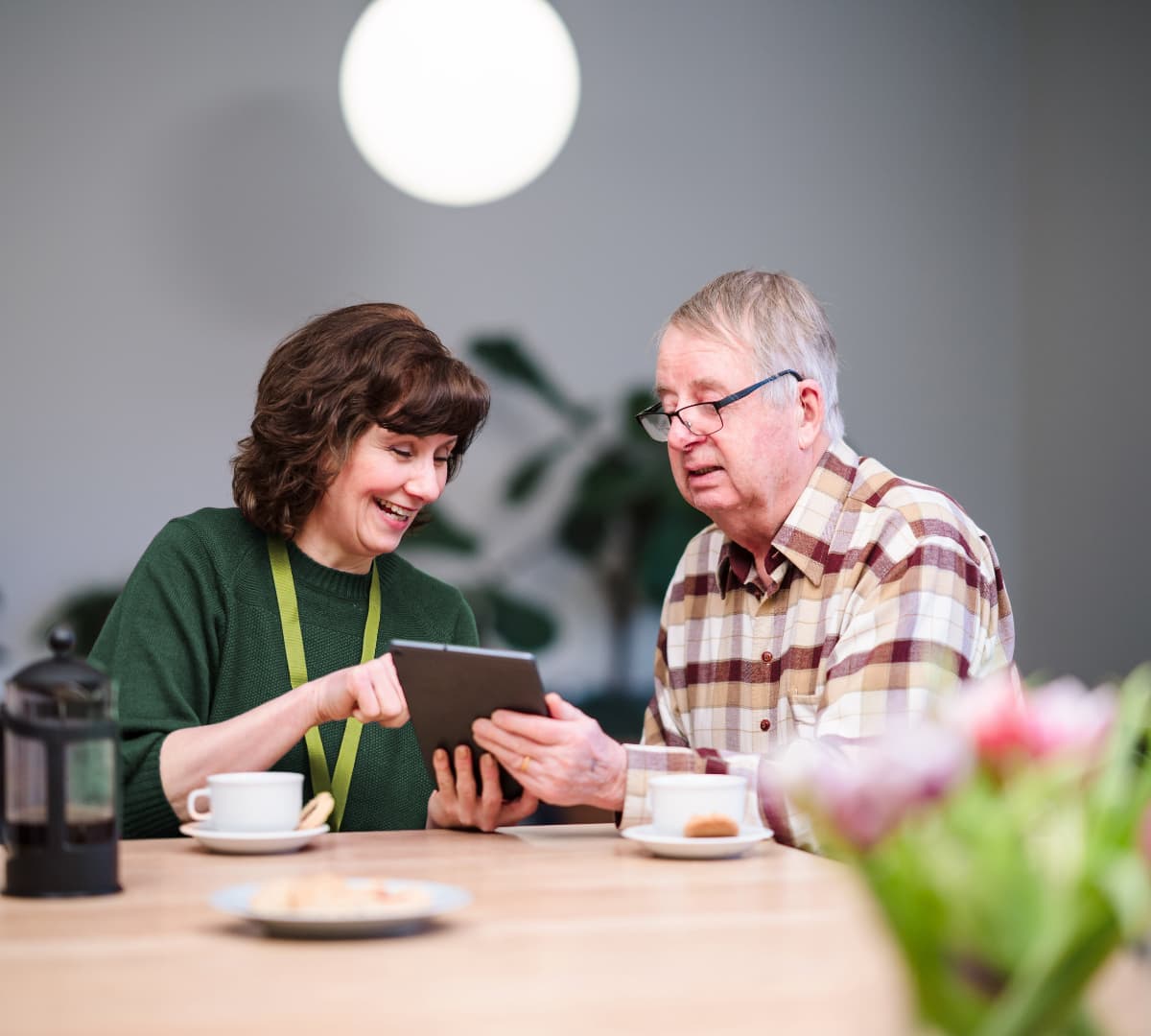 Two people using an IPAD while chatting together