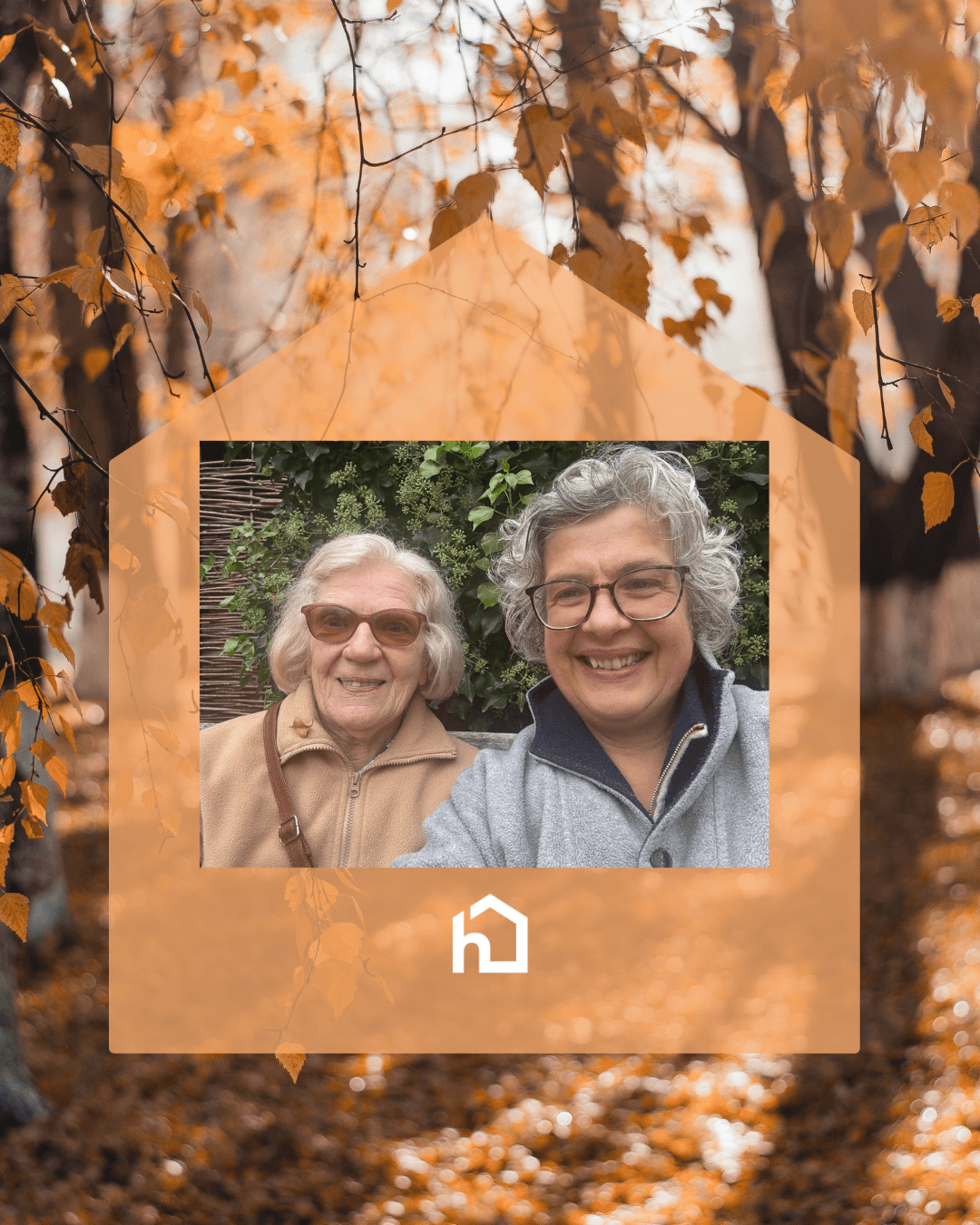 Two smiling older women taking a selfie, framed by a house shape over an autumn forest background. - Home Instead