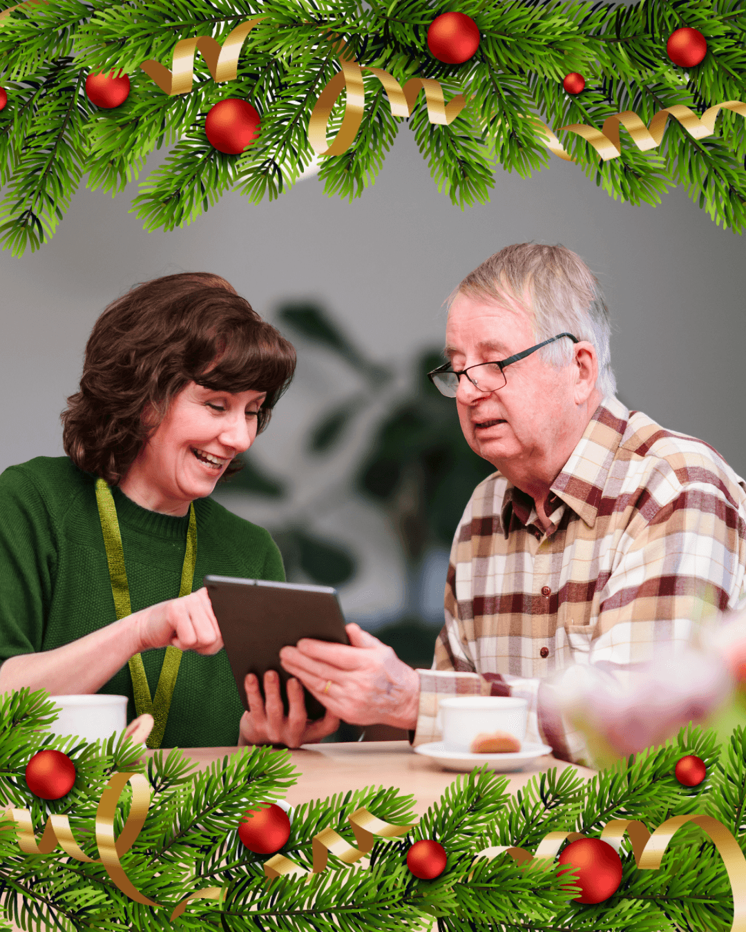 A woman and older man smile at a tablet, framed by festive Christmas decorations. - Home Instead